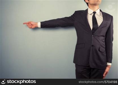 A young businessman is pointing left