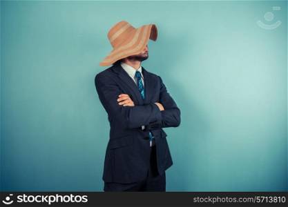 A young businessman is wearing a large beach hat