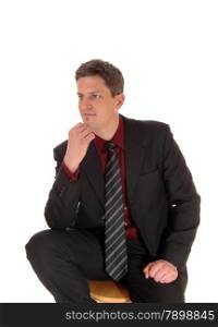 A young businessman sitting isolated for white background with his handon his chin, thinking.