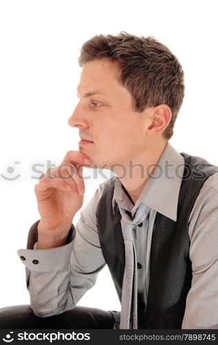 A young businessman sitting isolated for white background with one hand onhis chin in a grey shirt, vest and tie.