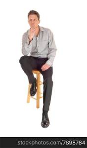 A young businessman sitting isolated for white background with one hand onhis chin in a grey shirt.