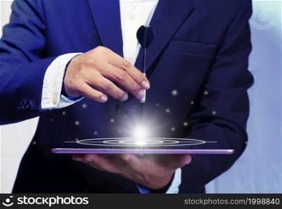 A young businessman uses the darts embroidered onto the tablet abstract to set goals to invest in his corporate business in his planning for the coming year.