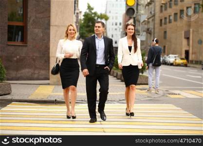 A young businessman walking on the street with their secretaries, outdoor summer street