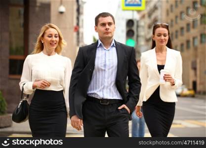 A young businessman walking on the street with their secretaries, outdoor summer street