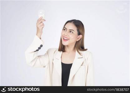 A young businesswoman is holding Light bulb wearing suit over white background studio
