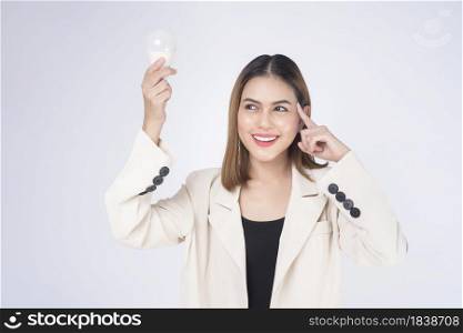 A young businesswoman is holding Light bulb wearing suit over white background studio