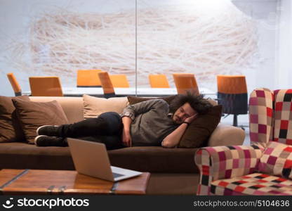 A young casual businessman sleeping on a sofa during a work break in a creative office