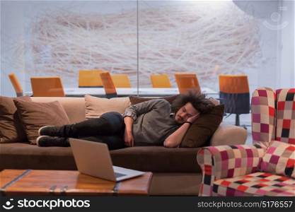 A young casual businessman sleeping on a sofa during a work break in a creative office