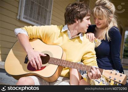 A young caucasian man in love playing guitar and singing to his girlfriend
