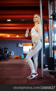 a young Caucasian woman in a white sports uniform is standing at the simulator and drinking water from a bottle . not a professional athlete, a beginner.. a young Caucasian woman in a white sports uniform is standing at the simulator and drinking water from a bottle . not a professional athlete, a beginner