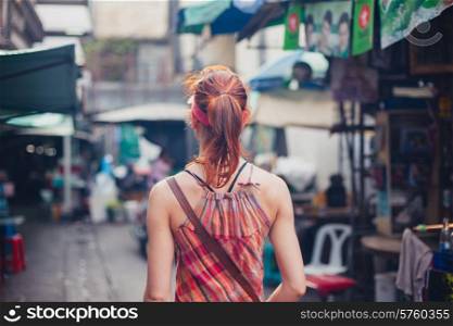 A young caucasian woman is walking on the street in an Asian country