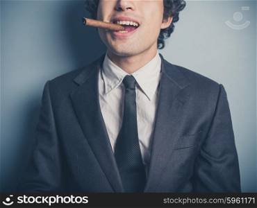A young confident businessman is smoking a cigar