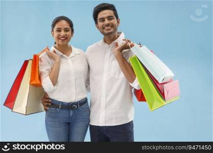 A YOUNG COUPLE HAPPILY STANDING IN FRONT OF CAMERA AFTER SHOPPING