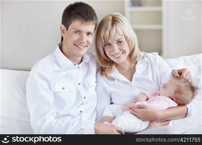 A young couple holding a baby at home