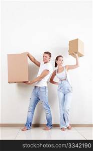 A young couple holds boxes in apartment