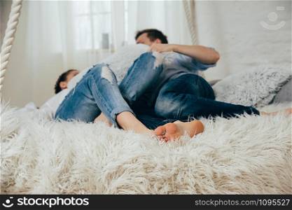 A young couple in blue jeans having fun on a hanging bed