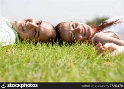 A young couple laying down and relaxing on a grass lawn