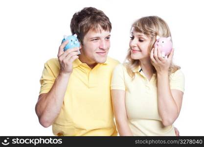 A young couple listening to their piggy banks, can be used for finance or saving concept