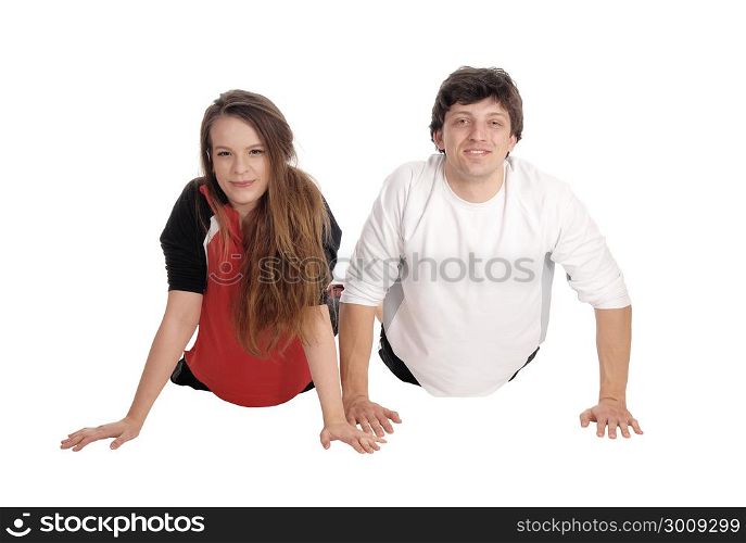 A young couple lying on the floor side by side and exercising inpunch-up?s, smiling, isolated for white background