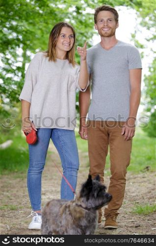a young couple walking a dog in the spring park