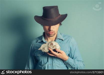 A young cowboy is holding an animal skull