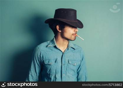 A young cowboy is smoking a cigarette