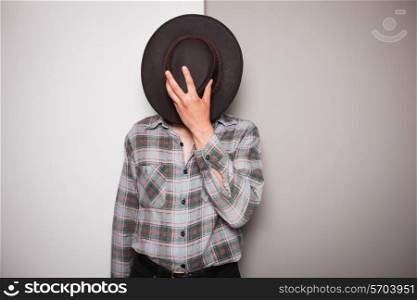 A young cowboy is standing a against a green and white background
