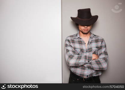 A young cowboy is standing a against a green and white background