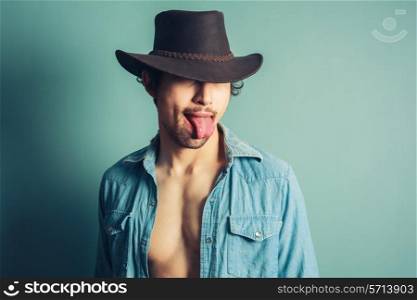 A young cowboy is sticking out his tongue