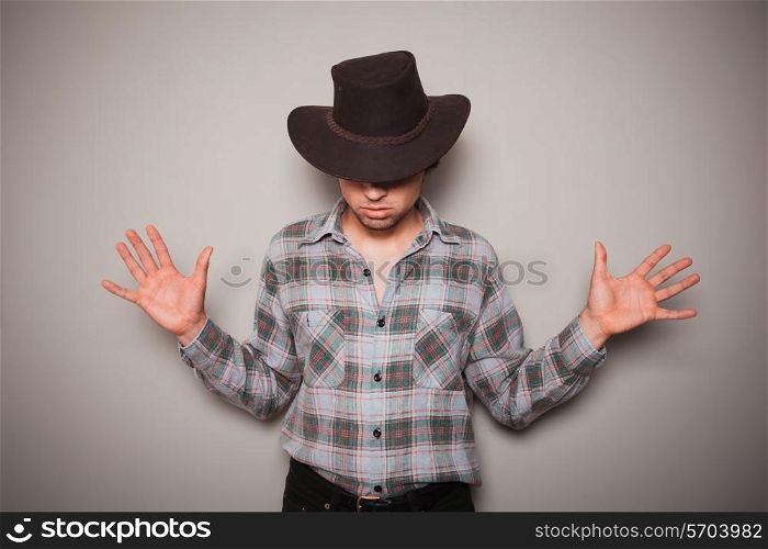 A young cowboy wearing a plaid shirt is posing against a green wall