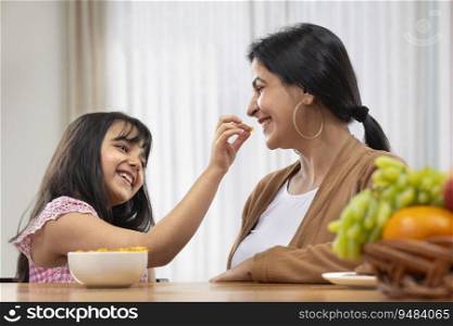 A YOUNG DAUGHTER HAPPILY GIVING NAMKEEN TO MOTHER