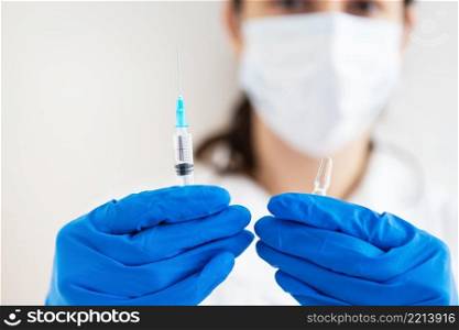 A young doctor with a syringe and a vaccine in his hands. Doctor indoors makes vaccination. A woman in a medical office. Vaccination against influenza and viruses. A young doctor with a syringe and a vaccine in his hands. Doctor indoors makes vaccination. A woman in a medical office. Vaccination against influenza and viruses.