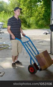 A young employee carries a package with handtruck