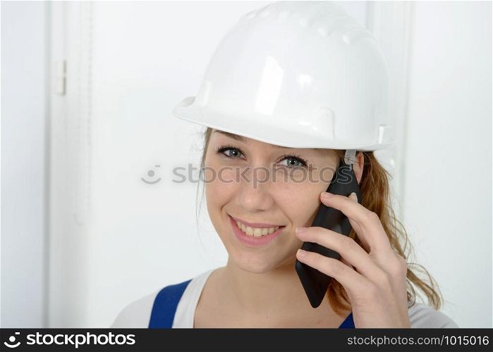 a young engineer woman with safety hard hat talking on phone