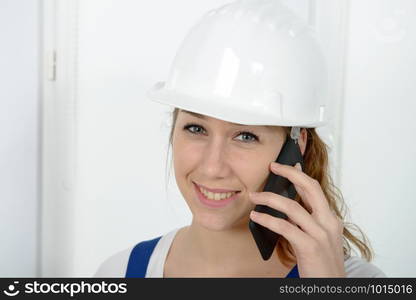 a young engineer woman with safety hard hat talking on phone