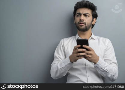 A YOUNG EXECUTIVE LOOKING AWAY IN CONFUSION WHILE USING MOBILE PHONE