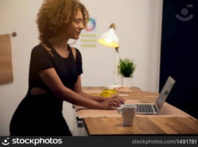 A young fashion designer on her atelier working with a laptop