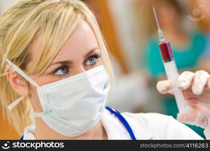 A young female doctor/nurse prepares a syringe with other medical staff out of focus in the background