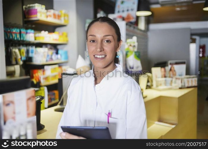 A Young female expert pharmacist is making notes while standing. Young female expert pharmacist is making notes while standing