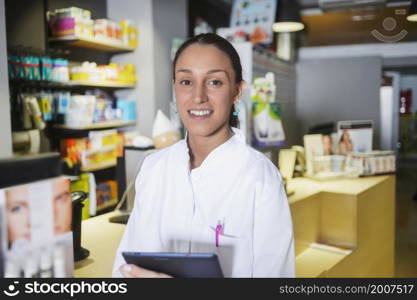 A Young female expert pharmacist is making notes while standing. Young female expert pharmacist is making notes while standing