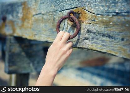 A young female hand is grabbing an old rusty chain attached to a wooden beam