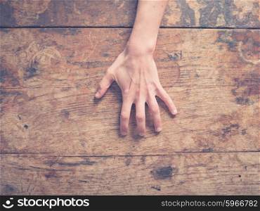 A young female hand is scratching a wooden table