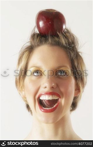 A young female model holds apple on her head like a target. .