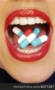 A young female mouth close up with pills. .