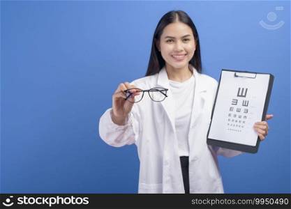 A young female ophthalmologist with glasses holding eye chart over blue background studio, healthcare concept. Young female ophthalmologist with glasses holding eye chart over blue background studio, healthcare concept