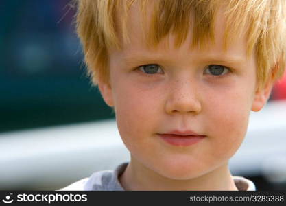 A young freckled boy looks enigmatically into the camera