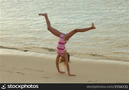 A young girl (6-8) doing cartwheels on a beach, Moorea, Tahiti, French Polynesia, South Pacific