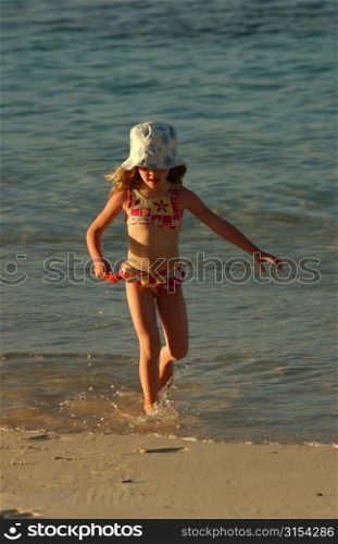 A young girl (6-8) playing on a beach, Moorea, Tahiti, French Polynesia, South Pacific