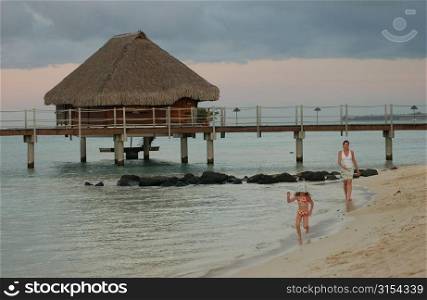 A young girl (6-8) playing with her mother on a beach, Moorea, Tahiti, French Polynesia, South Pacific