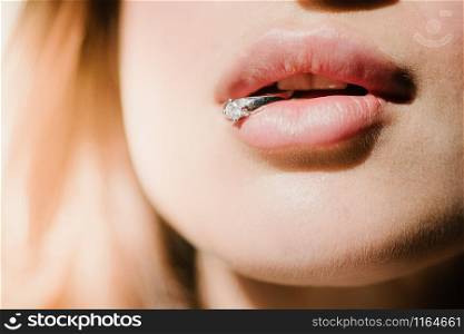 A young girl holds a ring with her lips. A ring in a woman&rsquo;s mouth. A woman holds a wedding ring with her teeth. A young girl holds a ring in her lips. A ring in a woman&rsquo;s mouth